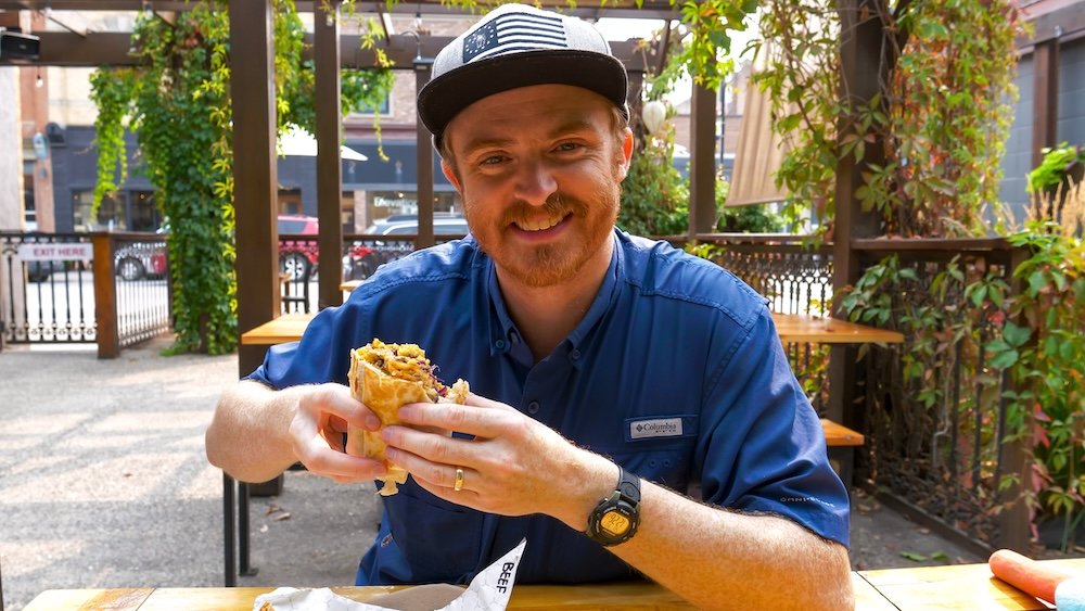 Luchadoro Burrito Co patio in Fernie, BC with Nomadic Samuel enjoying a Beefy Boy burrito Luchadoro Burrito Co in Fernie, British Columbia, with Nomadic Samuel enjoying patio season while eating the Beefy Boy burrito, highlighting Fernie’s casual food scene, sunny outdoor dining, and laid-back mountain town vibes during a long weekend visit.