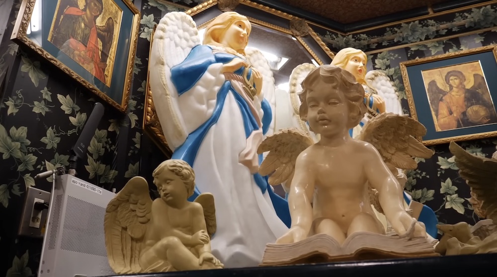 Decoración temática Angels’ Chatter en la sucursal de Lucky Pierrot cerca de la Torre Goryokaku, Hakodate, Hokkaido, Japón Estante con figuras de ángeles dentro de un restaurante Lucky Pierrot en Hakodate, Hokkaido, Japón, con una estatua grande de ángel azul y blanco, querubines, cuadros con marcos dorados y empapelado oscuro con hiedras.