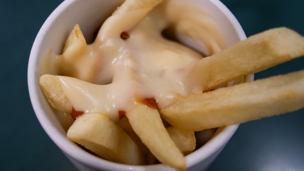 Papas fritas con salsa y queso en taza en Lucky Pierrot cerca de la Torre Goryokaku, Hakodate, Hokkaido, Japón Primer plano de papas fritas en una taza blanca cubiertas con salsa cremosa de queso derretido y manchas de salsa marrón rojiza en un restaurante Lucky Pierrot en Hakodate, Hokkaido, Japón.