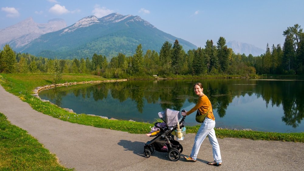 Maiden Lake Fernie BC stroller walk with Mount Trinity reflections and family-friendly lakeside path Maiden Lake in Fernie, British Columbia, with Mount Trinity reflections as Audrey Bergner pushes baby Aurelia in a stroller along the paved lakeside path—an easy, kid-friendly walk with big mountain views.