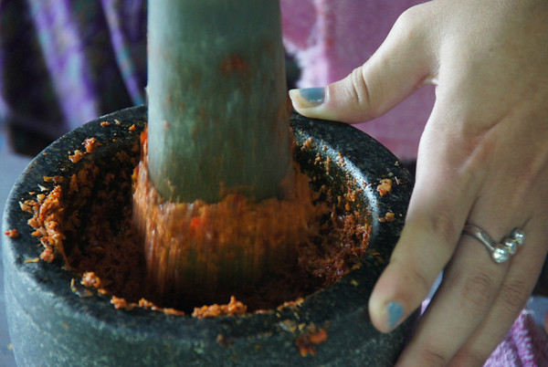 Making Thai curry paste with a pestle and mortar and pounding it by hand in Chiang Mai, Thailand.