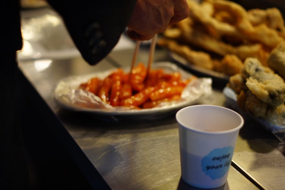 Man eating tteokbokki in Insadong, South Korea at night 