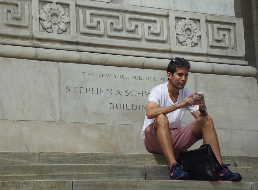 Man texting on his cellphone outside of the New York Public Library