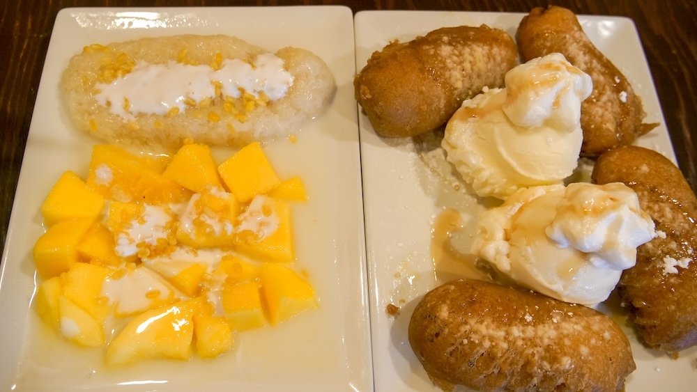 Mango sticky rice and deep-fried banana dessert served at Family Thai Restaurant in Cranbrook, British Columbia, featuring sweet mango with coconut sticky rice alongside crispy fried bananas topped with vanilla ice cream and whipped cream after a comforting Thai dinner.