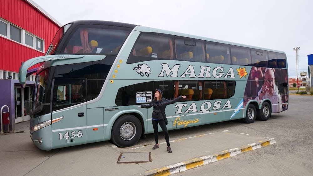 Marga Taqsa Bus in El Calafate Santa Cruz and Patagonia Seasonal Transit Planning with Audrey Bergner Audrey Bergner posing beside a Marga Taqsa bus in El Calafate, Santa Cruz, showing how Patagonia summer versus shoulder-season travel depends heavily on bus schedules, seat availability and regional transit timing.