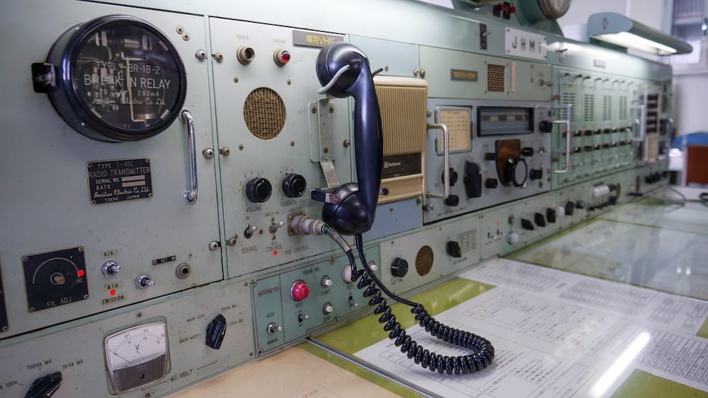 Equipos antiguos de radio y comunicaciones dentro de Seikan Ferry Memorial Ship Mashu-maru, en Hakodate, Hokkaido, Japón, con un auricular negro, perillas, interruptores y paneles de control.