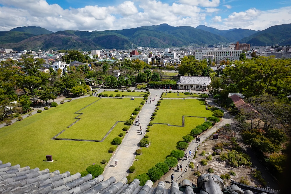 High vantage point views from Matsumoto Castle overlooking the courtyard, city and mountains in the background 
