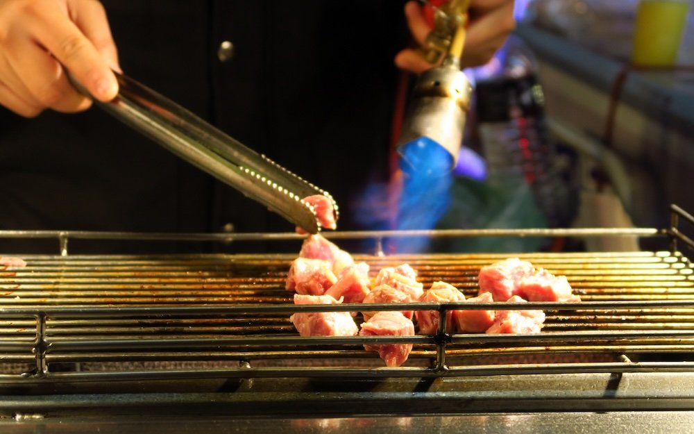 Meat being cooked by a flame in Taipei, Taiwan as street food to try 