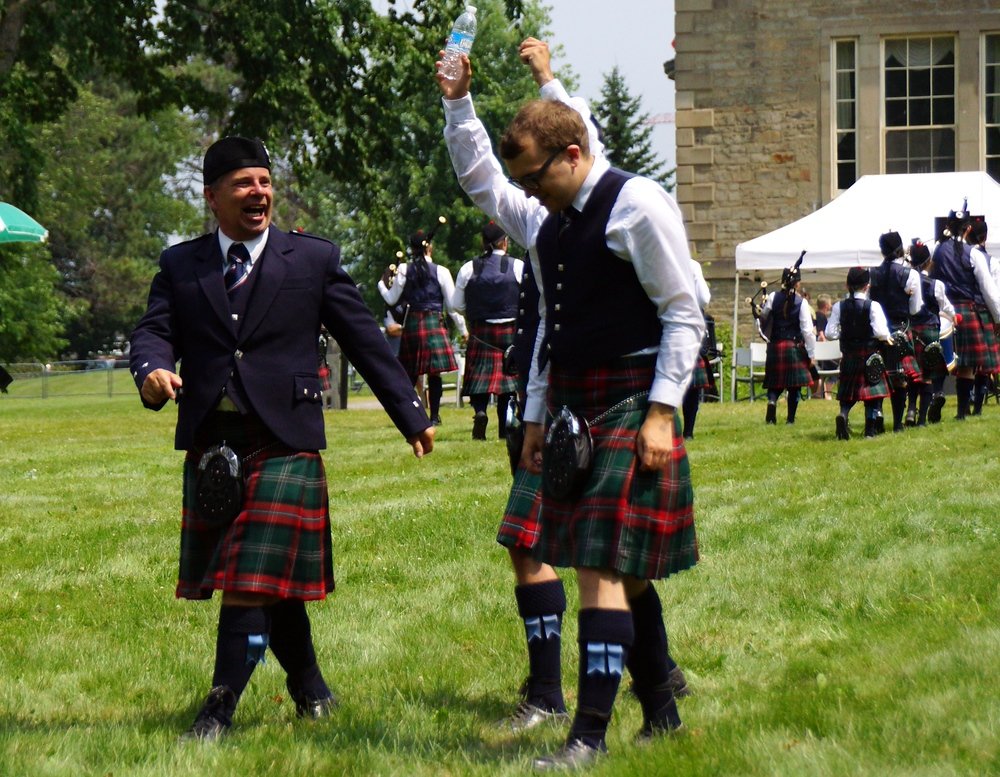 Men sharing a laugh as the walk along the grass at the New Brunswick Highland Games in Fredericton