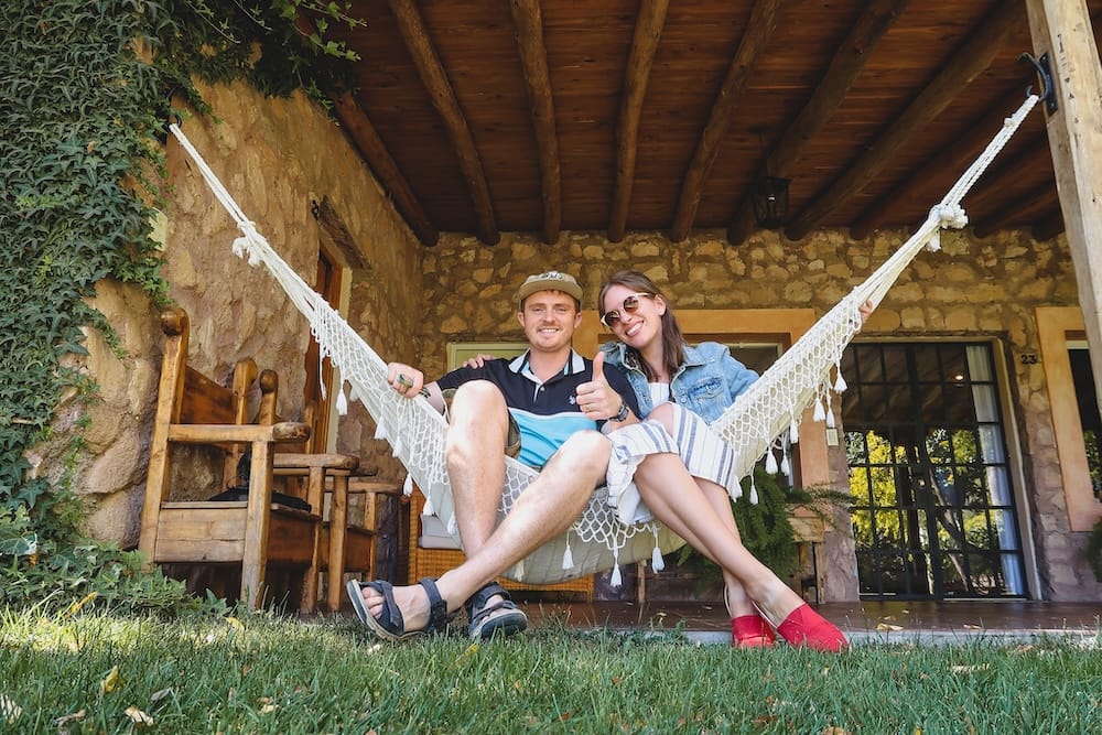 Mendoza wine country at Finca Adalgisa with Samuel Jeffery and Audrey Bergner relaxing in a hammock outside a stone guesthouse, documenting vineyard hospitality, Malbec culture, and boutique lodging for Project 23.