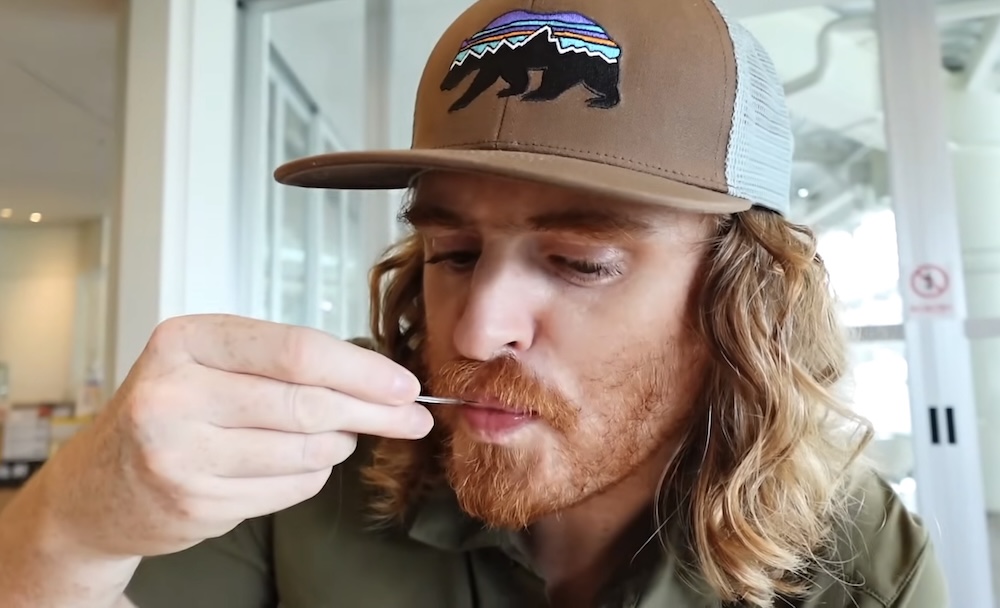 Samuel Jeffery con una gorra trucker marrón con el logo de un oso come una cucharada de gelato en un luminoso salón interior de Milkissimo dentro de la Torre Goryokaku en Hakodate, Hokkaido, Japón.