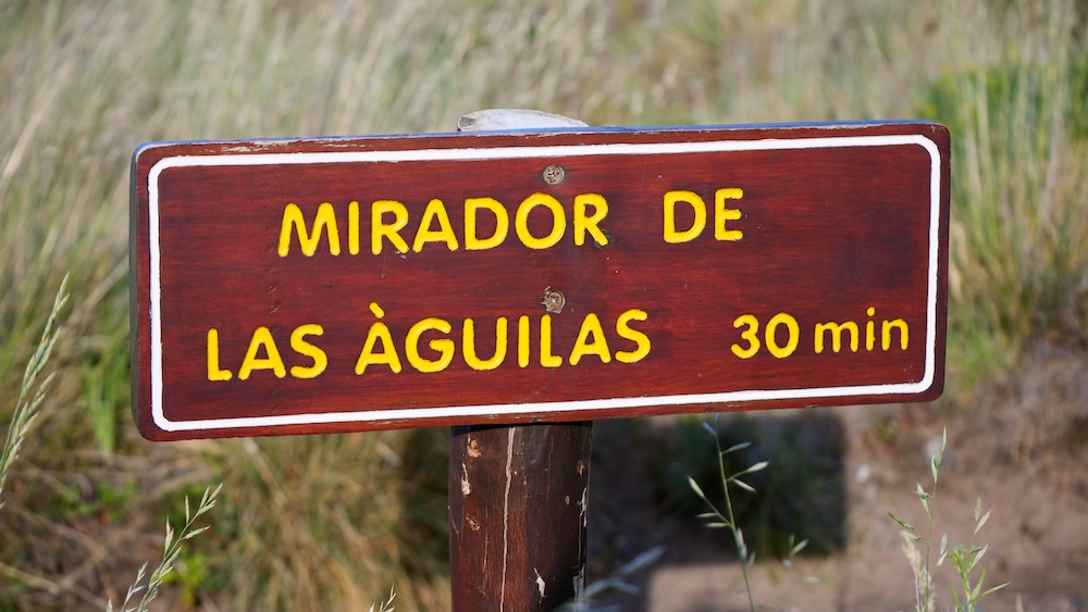 Mirador de las Águilas 30-minute trail sign in El Chaltén A wooden trail sign reading “Mirador de las Águilas – 30 min” marks the path toward the viewpoint in El Chaltén, highlighting the short add-on hike beyond Mirador de los Cóndores.