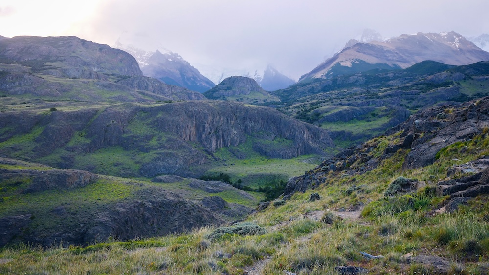 Rugged Patagonian trail near Mirador de los Cóndores in El Chaltén Rugged Patagonian hills and rocky cliffs line the trail near Mirador de los Cóndores in El Chaltén, where grassy slopes, dramatic textures, and distant peaks create a wild hiking atmosphere.