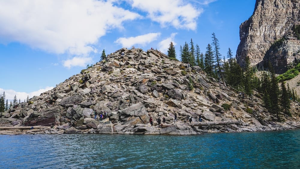 Moraine Lake Rockpile in Banff National Park, Alberta, Canada with rocky viewpoint and turquoise lake The rocky Rockpile viewpoint beside Moraine Lake in Banff National Park, Alberta, Canada, with visitors climbing over boulders above turquoise water and steep mountain cliffs.