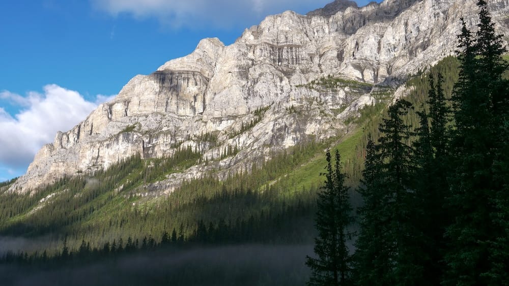 Morning mist, mountain view, Halfway Lodge, Banff National Park, Alberta, Canada Morning mist settles over a forested valley beneath a limestone mountain ridge near Halfway Lodge in Banff National Park, Alberta, Canada, during a six-day backcountry horseback trek.
