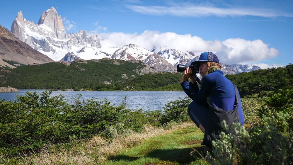 Mount Fitz Roy Skyline Near El Chaltén, Patagonia, Argentina, Photographed by Audrey Bergner Audrey Bergner photographs the snow-covered Mount Fitz Roy skyline beside a blue lake near El Chaltén, Santa Cruz, Patagonia, Argentina, with forested foothills and low clouds below the granite peaks.