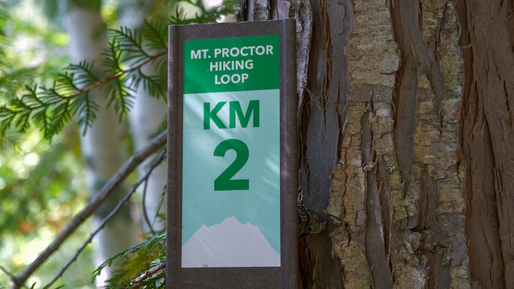 Mt Proctor Hiking Loop KM 2 trail marker posted along the Fairy Creek Falls route in Fernie, British Columbia, showing distance information for hikers exploring the interconnected forest trails near the popular waterfall hike.
