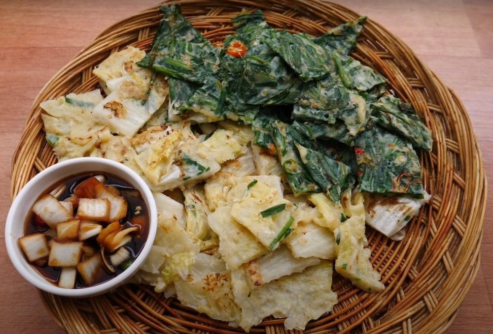 Multiple Korean pancakes cut up in bite sized pieces with dipping sauce in Daegu, Korea 