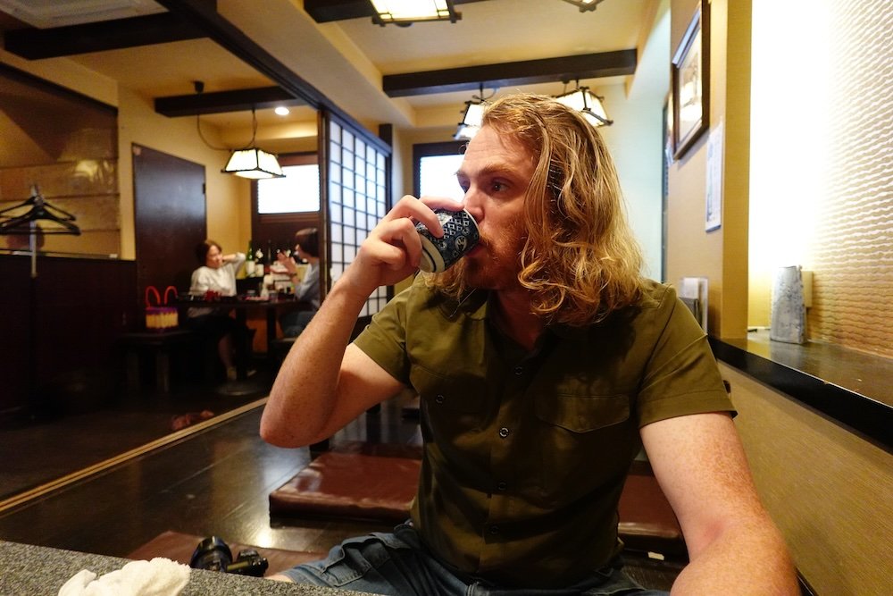 Nomadic Samuel drinking sake at a restaurant in Niigata, Japan 