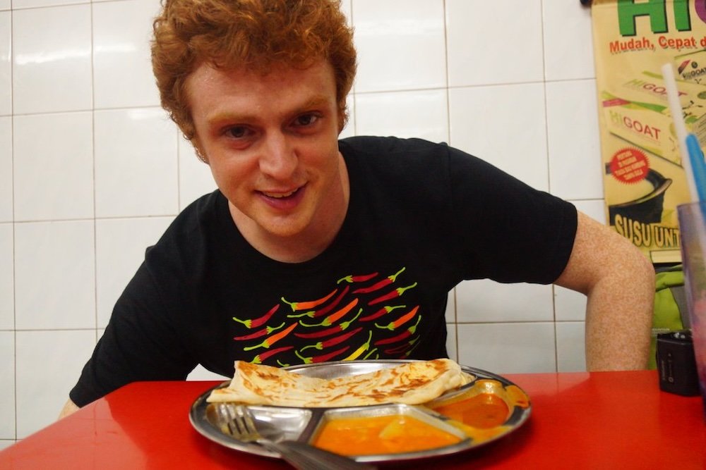 Nomadic Samuel enjoying curry near the Batu Caves, Malaysia 