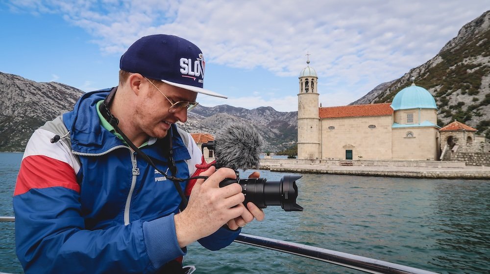 Nomadic Samuel enjoying filming and taking photos while on a boat tour in Perast, Montenegro 