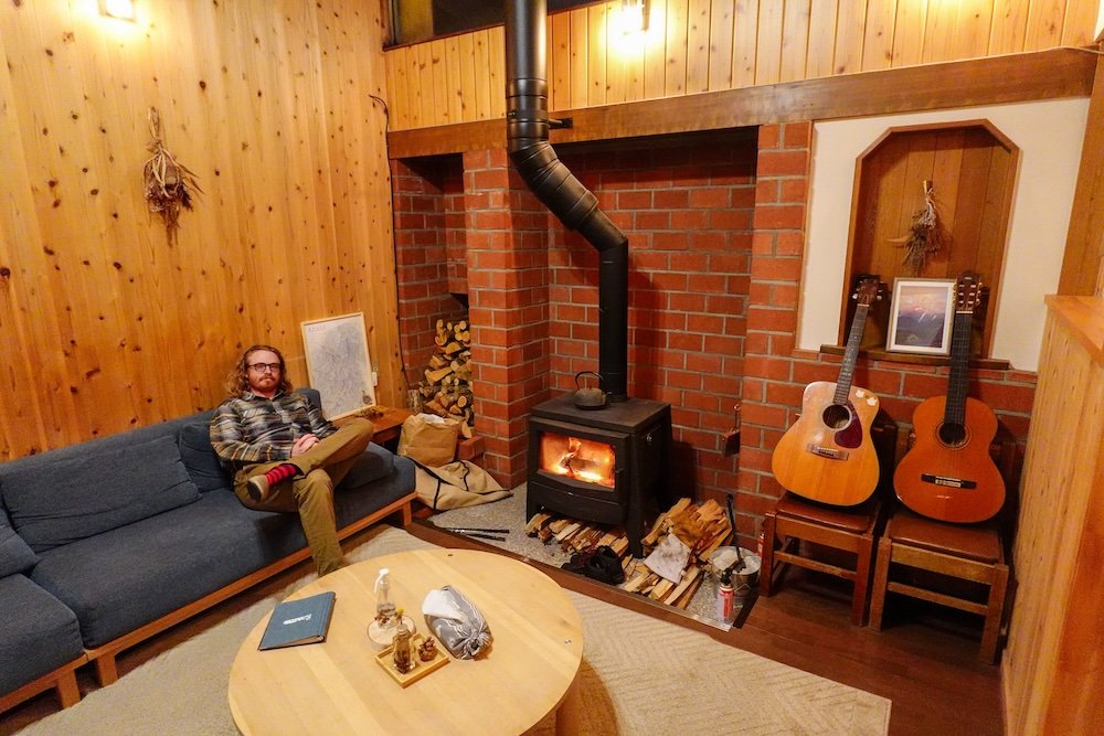 Nomadic Samuel enjoying a warm fire and cozy space after exploring rural Japan in the Nagano province 