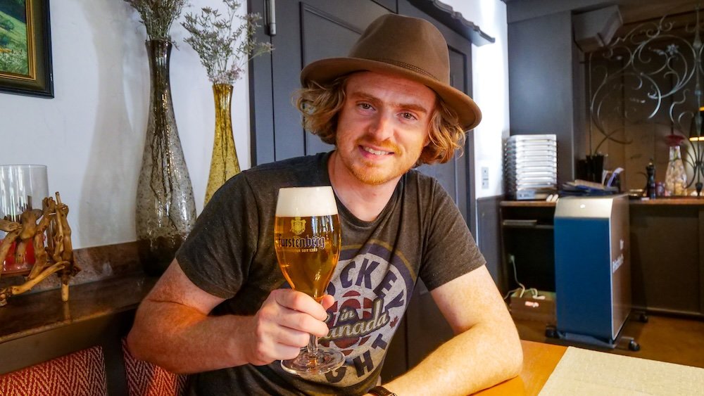 Nomadic Samuel holding a beer whilst visiting the Black Forest, Germany 