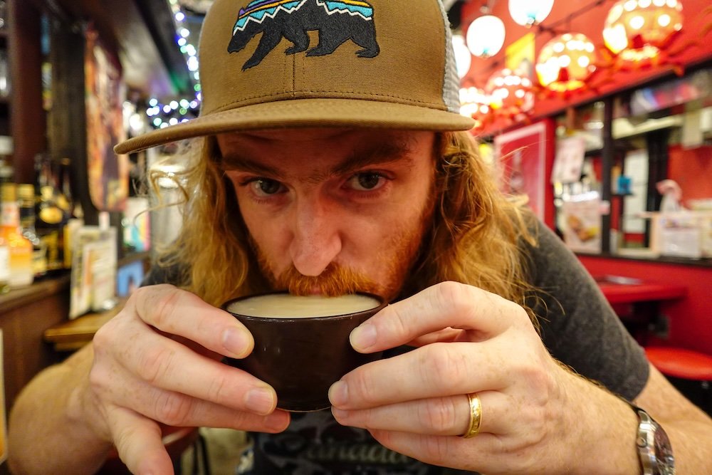 Nomadic Samuel sipping on a traditional Japanese drink 