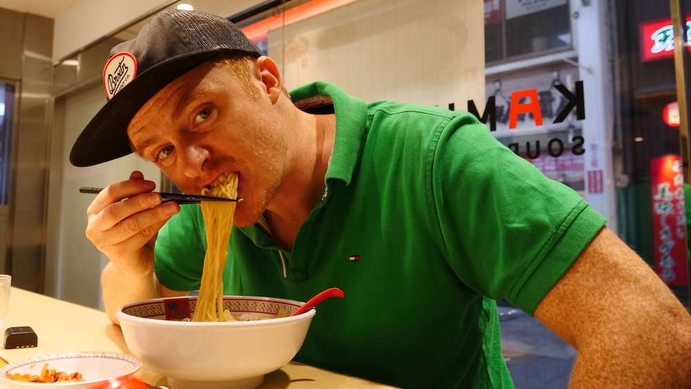 Nomadic Samuel slurping noodles ramen in Osaka, Japan 