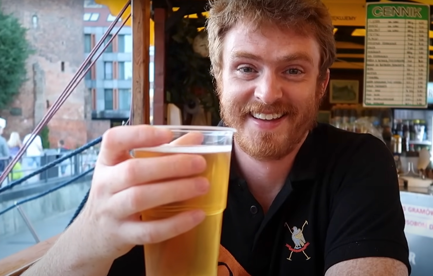 Nomadic Samuel smiling and enjoying a pint of beer at Floating Fish and Chips Restaurant at Oscars in Gdansk, Poland