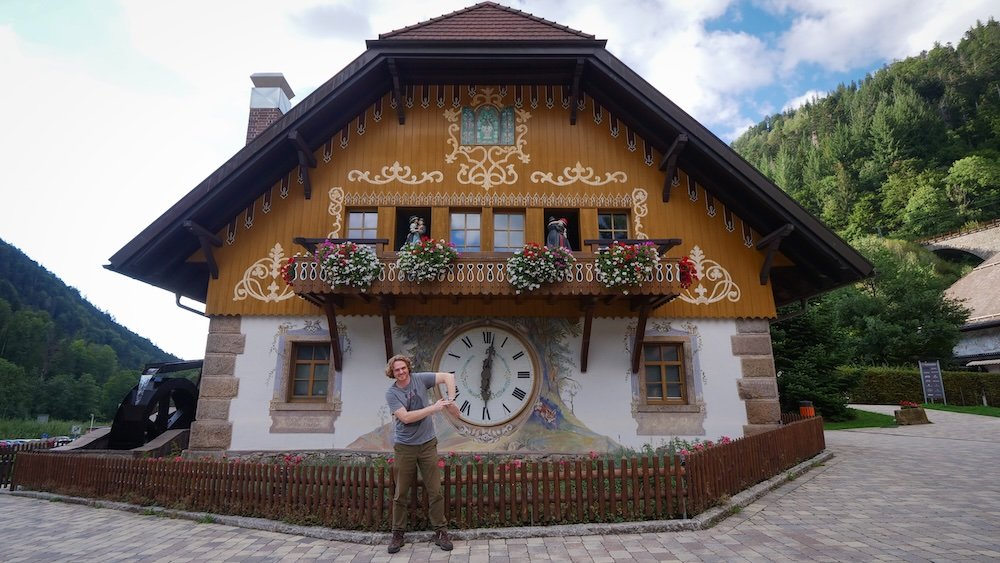 Nomadic Samuel standing outside beside the Hofgut Sternen famed cuckoo clocks keeping time in the Black Forest, Germany 