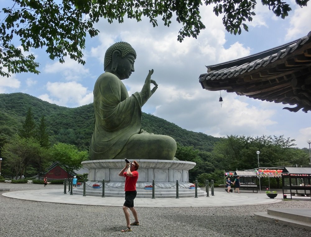 Nomadic Samuel taking photos by the giant Buddha statue in Cheonan, Korea 