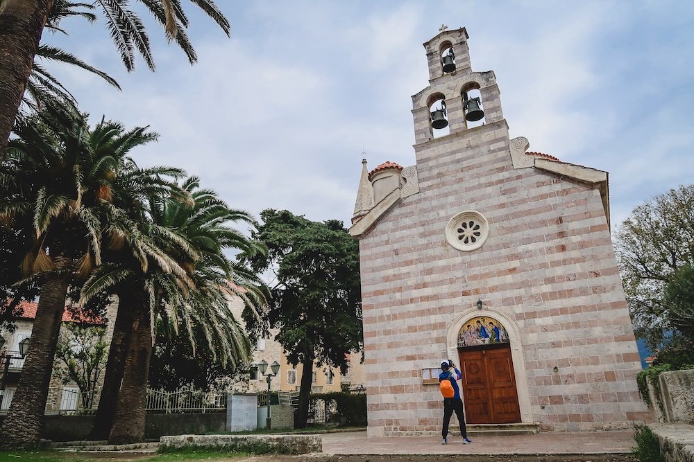 Nomadic Samuel taking photos of an impressive cathedral and church in Budva, Montenegro 