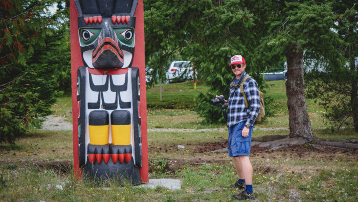 Nomadic Samuel taking photos of the totem poles in Alert Bay, BC, Canada