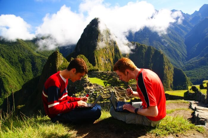 Nomadic Samuel travel blogging on top of Machu Picchu, Peru in a joking manner