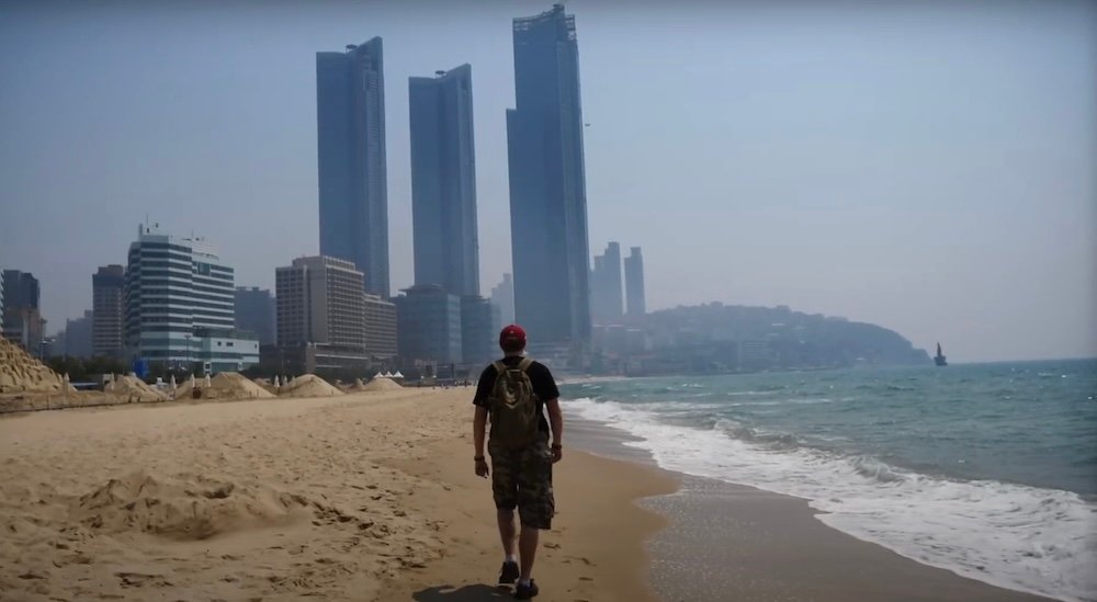 Nomadic Samuel walking along Haeundae beach in Busan, South Korea 