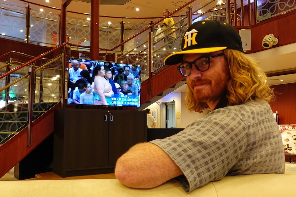 Nomadic Samuel watching a sumo match on the Japanese ferry 