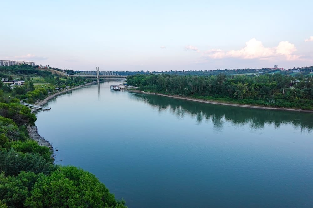Vista amplia del valle del North Saskatchewan River en Edmonton, Alberta, Canadá, con el río, abundante vegetación y un puente extendiéndose a través del paisaje.