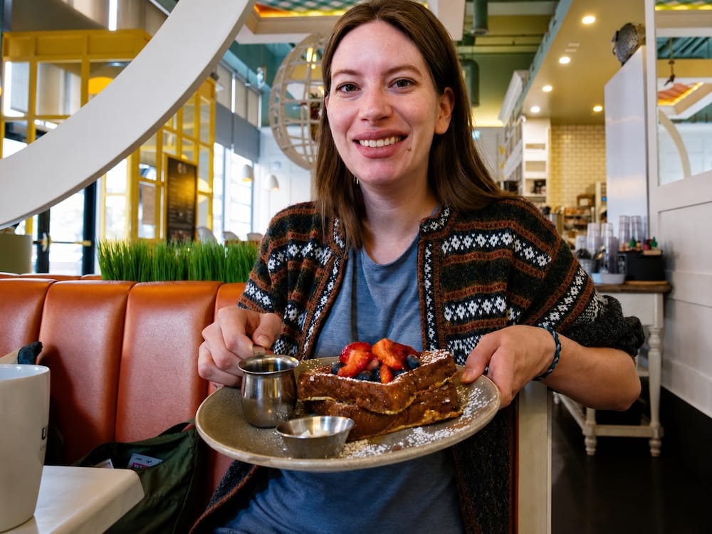 Audrey Bergner sonríe mientras sostiene un plato de gruesas tostadas francesas cubiertas con frutillas, arándanos y azúcar impalpable en OEB Breakfast Co. en el centro de Edmonton, Alberta, Canadá.