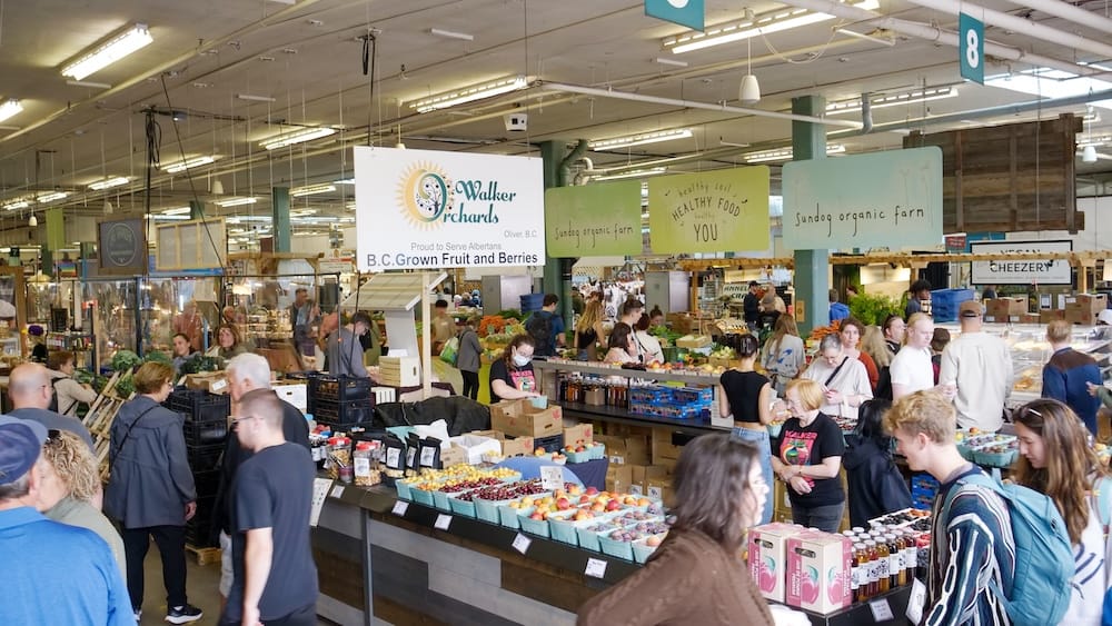 Busy Old Strathcona Farmers’ Market interior with produce vendors in Edmonton, Alberta, Canada Busy interior of the Old Strathcona Farmers’ Market with shoppers, produce stands, fruit baskets and vendor signs inside the former bus barn in Edmonton, Alberta, Canada.