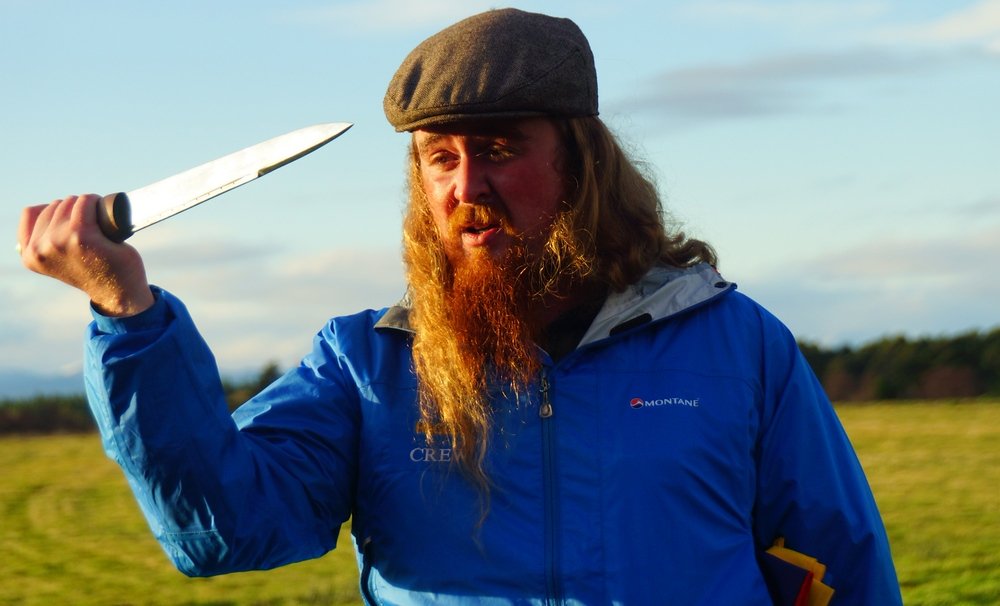 Our Haggis Adventures guide Dave with his distinct ginger beard at Culloden wielding a massive knife slash sword