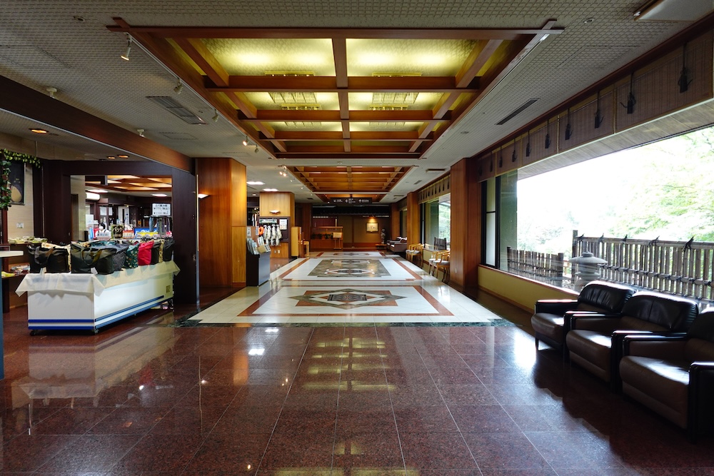 Lobby and garden windows at Park Hotel Miyabitei, a resort hotel in Noboribetsu Onsen, Hokkaido, Japan The lobby of Park Hotel Miyabitei, with polished stone floors, a coffered wooden ceiling, leather armchairs and tall windows facing a garden stone lantern, in Noboribetsu Onsen, Hokkaido, Japan.