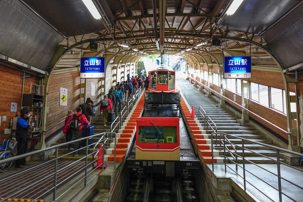 Passengers walking up the steps and boarding Tateyama Cable Car to being a journey from Tateyama Station to Bijodaira 