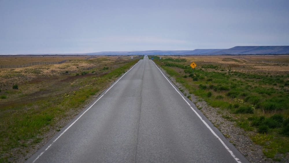Long empty road stretching across the Patagonian steppe toward El Calafate Argentina, highlighting vast distances, isolation, and the reality of long drives between destinations in one of the most remote travel regions in South America.