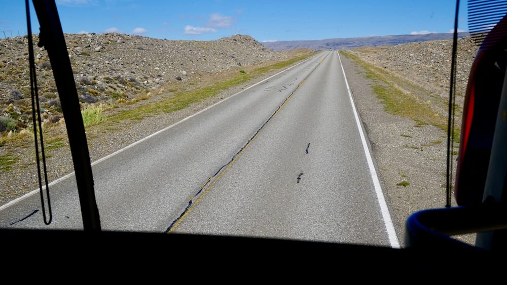 View from a long-distance bus on an empty Patagonian steppe highway near Puerto Natales, showing the remote overland routes where transport delays can quickly reshape travel plans.