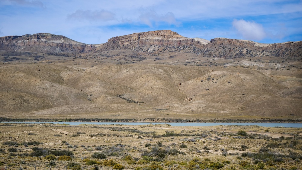 Wide-open Patagonian steppe and river views seen from the bus window while traveling from El Calafate to El Chaltén, showing the remote landscapes that make this journey part of the adventure itself.