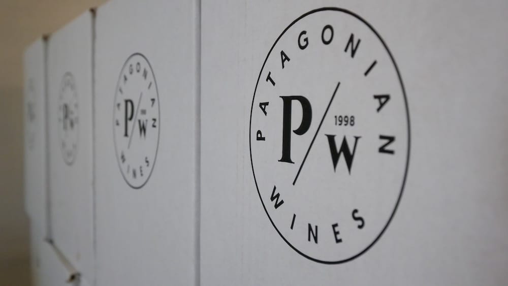 Patagonian Wines packaging and PW 1998 logo in El Hoyo, Chubut, Patagonia, Argentina White Patagonian Wines boxes display the circular PW 1998 logo in close-up at El Hoyo, Chubut, Patagonia, Argentina, with shallow focus emphasizing the winery’s minimalist packaging and brand identity.