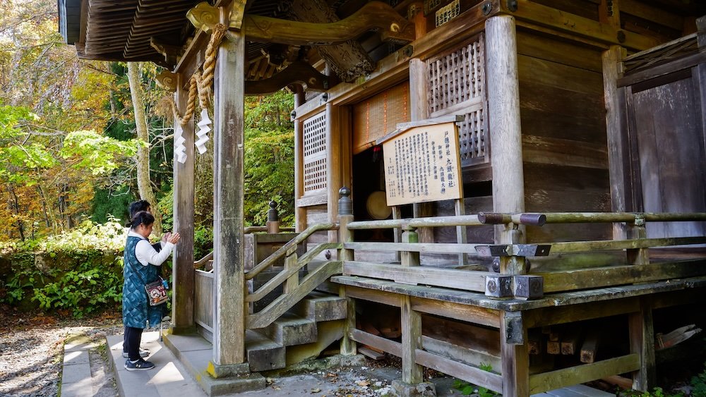 People praying and bowing outside Togakushi Shrine sacred site views on a day trip from Nagano city, Japan 