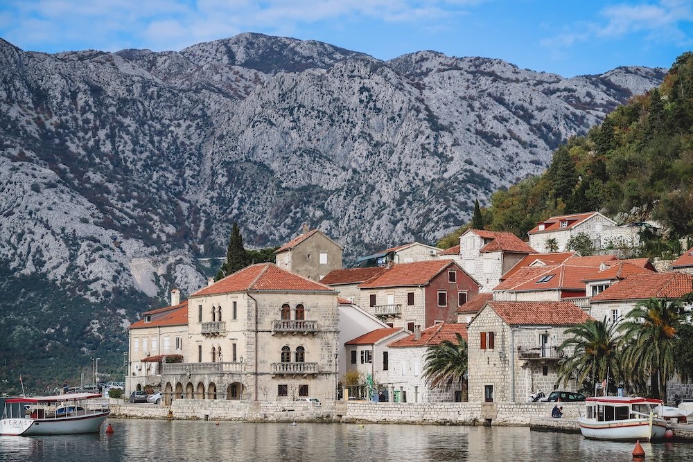 Perast traditional architecture with lake foreground and mountain backdrop in Montenegro 