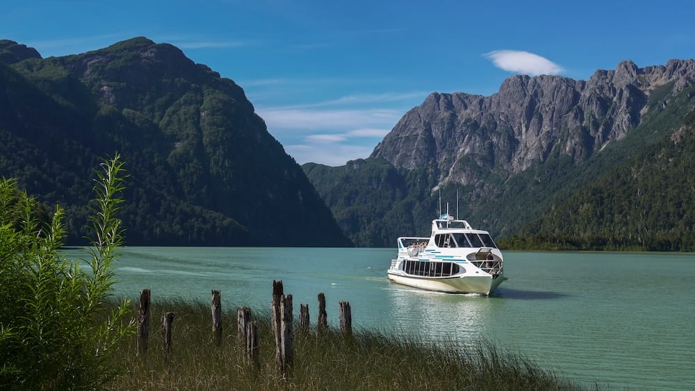 Catamaran near Puerto Blest on Nahuel Huapi Lake, Bariloche, Río Negro, Patagonia, Argentina A white catamaran cruises across the emerald water near Puerto Blest, framed by steep forested mountains and rocky ridges in Bariloche, Río Negro, Patagonia, Argentina.